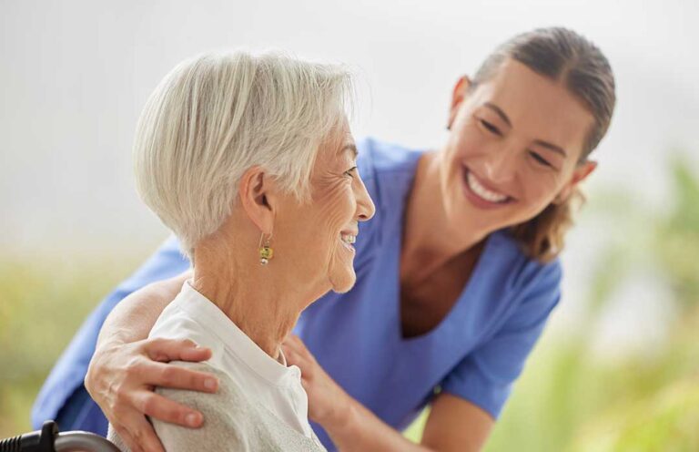 Two older adults enjoying a conversation in a bright, comfortable common area with natural light.