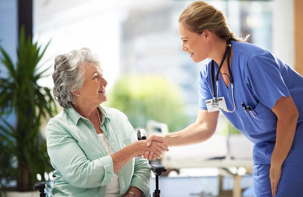 Senior using a cane while staff member describes a brightly lit, uncluttered assisted living hallway.