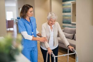 Staff member cleaning a handrail in a bright hallway while residents walk nearby.