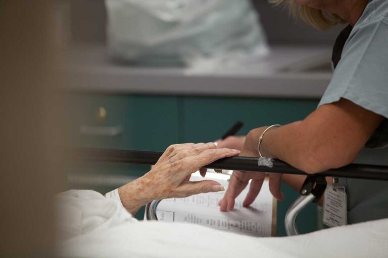Older adults sharing conversation at a small table in a bright assisted living common room.